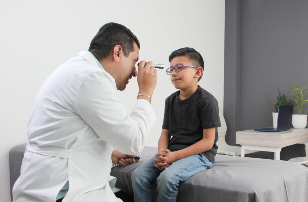 An eye doctor shining a light in a child's eye during an eye exam.