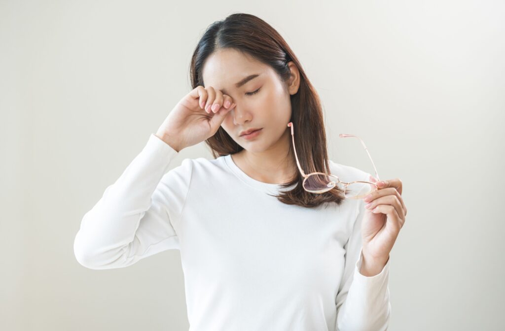 A woman rubbing her eyes due to dry eye symptoms.