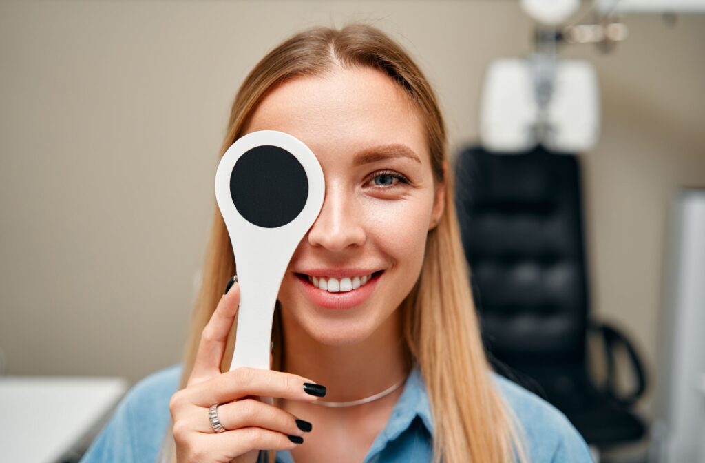 A smiling patient covers one eye during an eye exam.