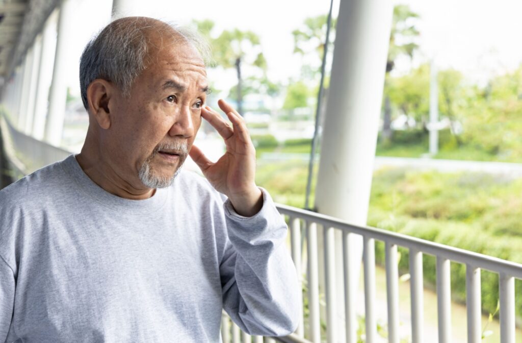 A senior experiencing dry itchy eyes from MGD while outside rubs their eye.