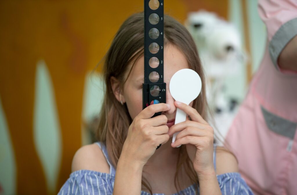 A child with amblyopia uses a paddle to cover one eye and looks through a lens with the other during vision therapy.
