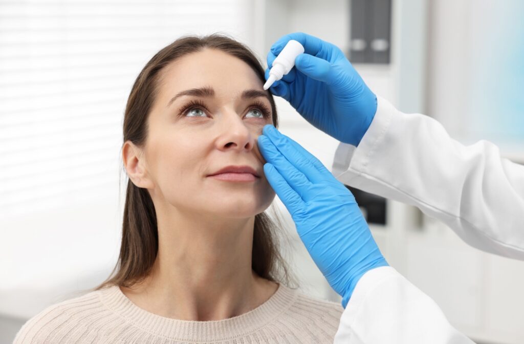 A patient keeps their eyes open while an optometrist carefully applies prescription eye drops to alleviate dry eye symptoms