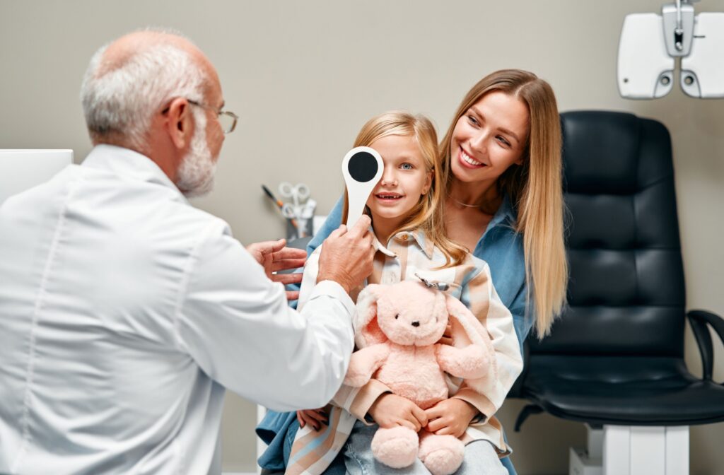 An eye doctor covers a young patient's eye for a visual assessment.
